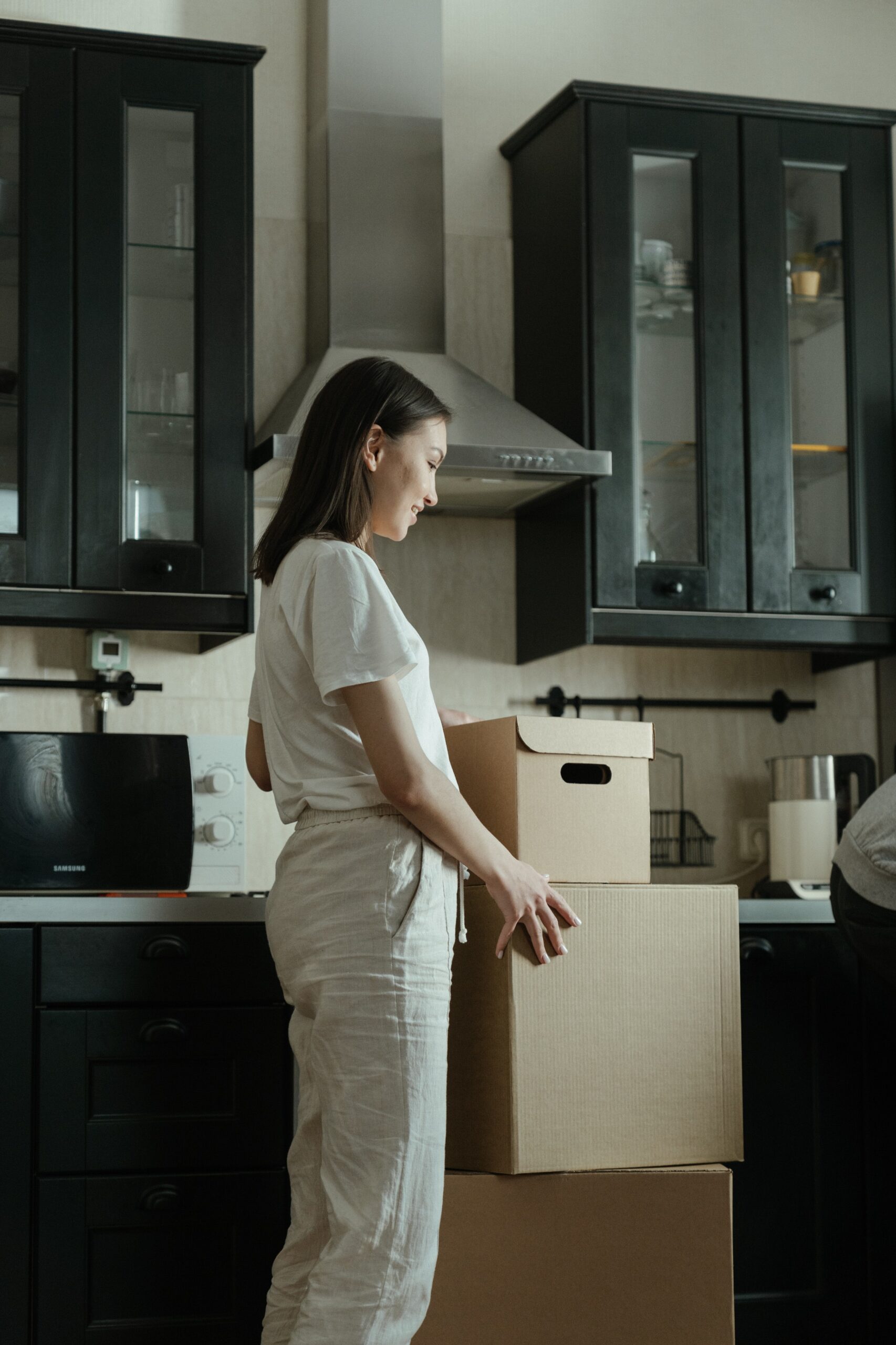 Woman standing in kitchen with boxes