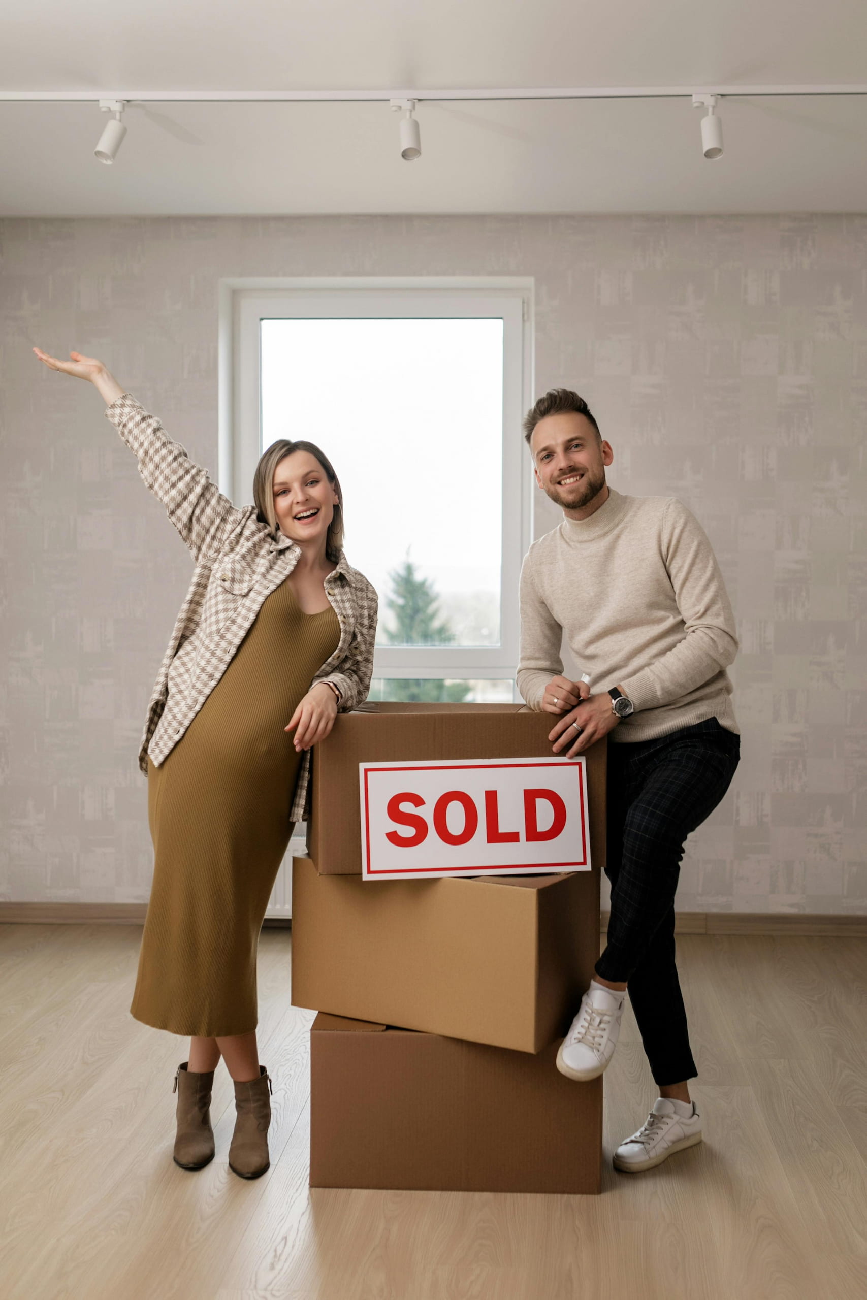 A happy couple standing in their new home with moving boxes labeled 'SOLD,' representing first-time homebuyers achieving their dream through down payment assistance programs.