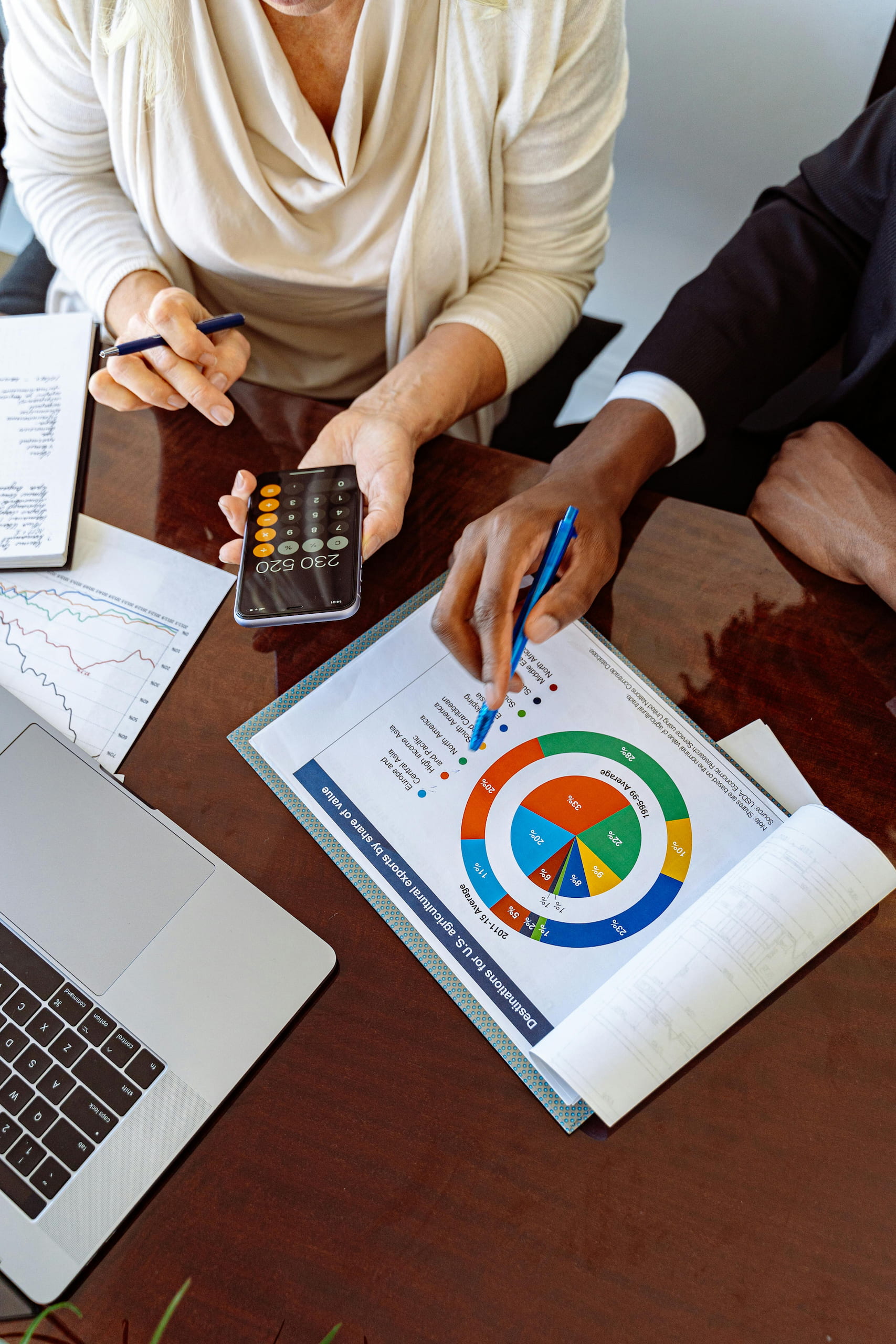 A financial advisor and a client discussing charts and calculations at a desk, illustrating how down payment assistance programs help first-time homebuyers navigate financial planning.