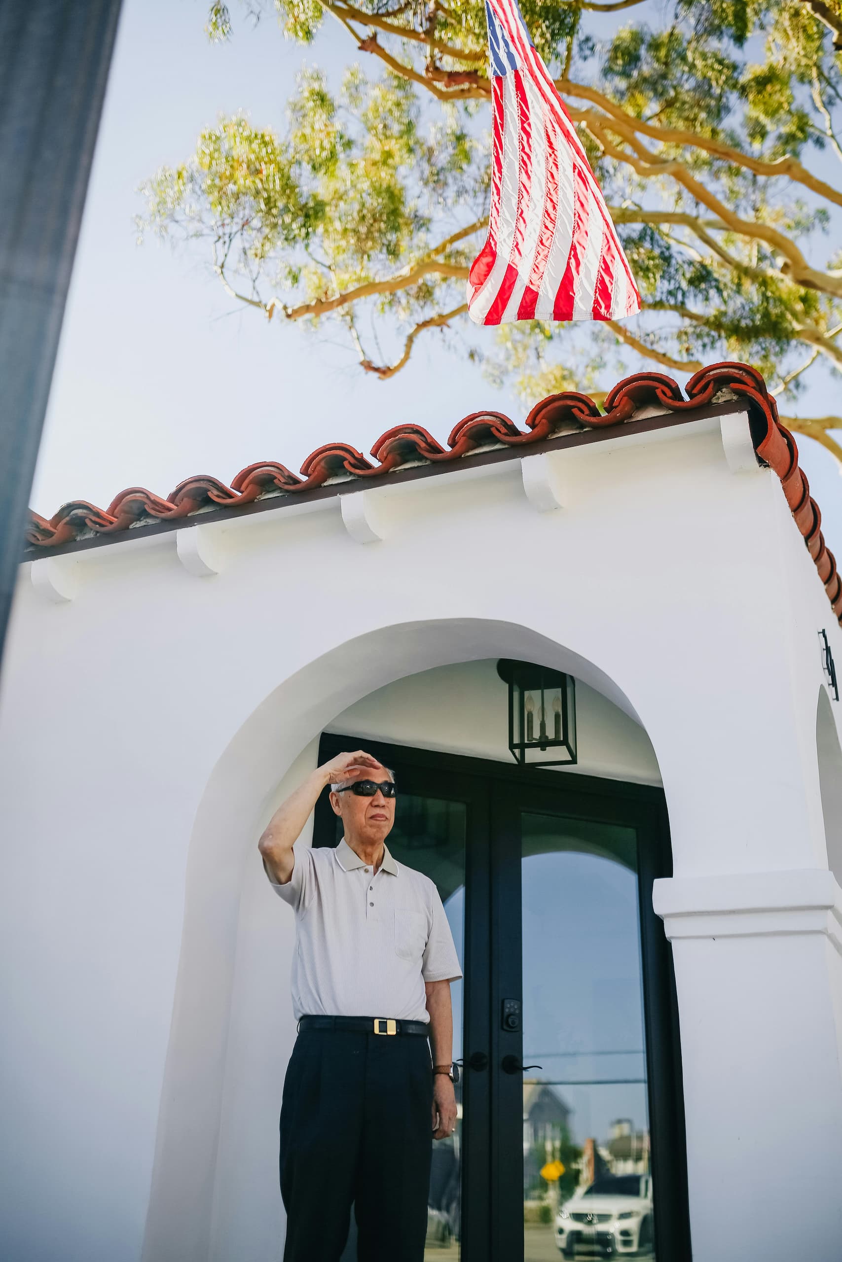 Veteran saluting the American flag outside a modern home, showcasing patriotism and the opportunities provided by VA Home Loans for veterans to achieve homeownership