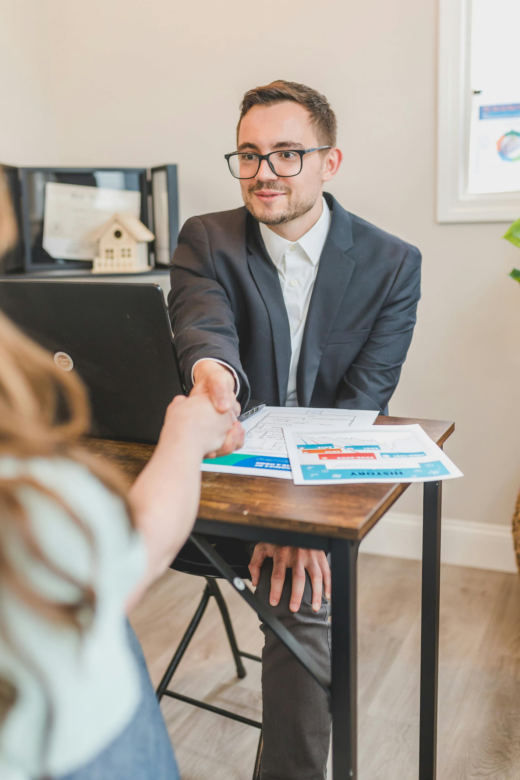 pexels-rdne-8293653 (1) A mortgage broker shaking hands with a client across a desk, symbolizing trust and successful partnership in real estate financing