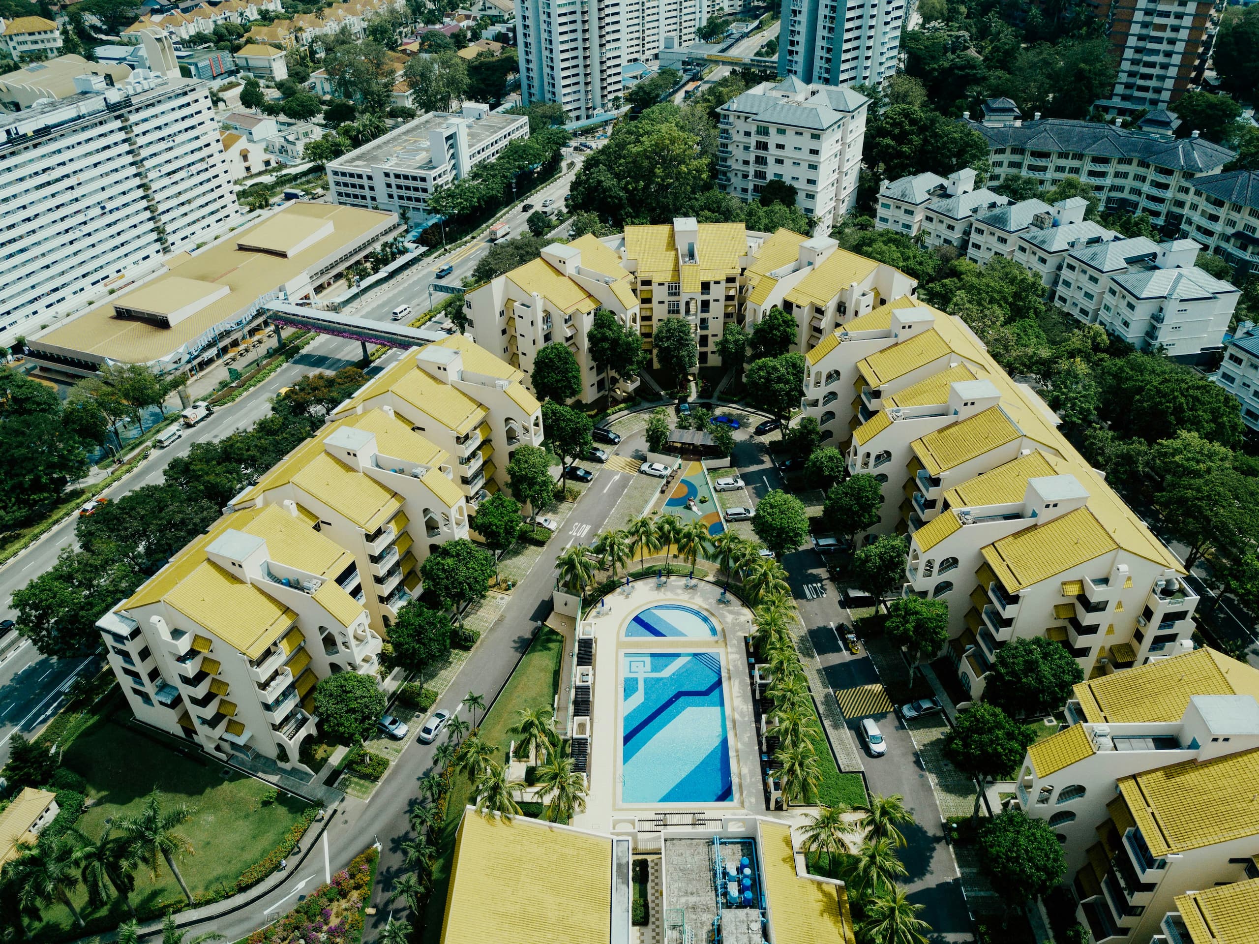 chuttersnap-Y-fO0Yy3qRs-unsplash (1) Aerial view of a residential community with a swimming pool, surrounded by multi-story homes, illustrating a well-maintained neighborhood governed by a homeowners association (HOA) for homebuyers.