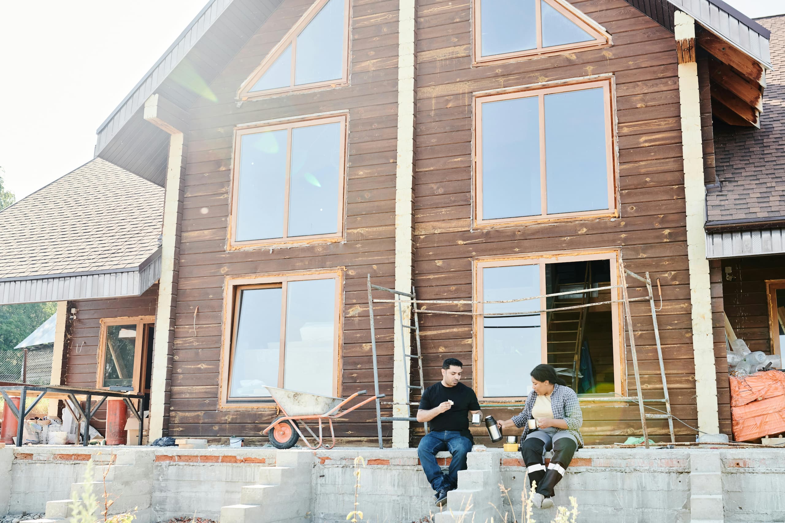 pexels-mikael-blomkvist-8961257 (1) A couple sitting outside a fixer-upper home under renovation, representing real estate investment opportunities and the process of transforming a property through renovation.